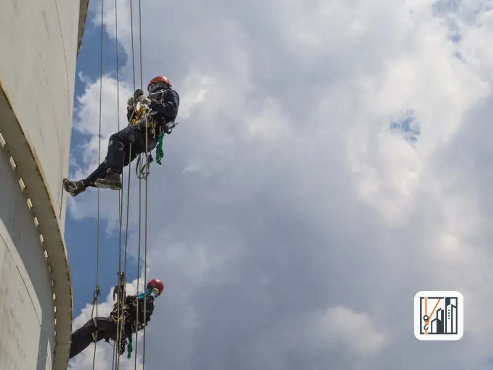 Técnicos de trabajos verticales revisando una fachada colgados de cuerdas
